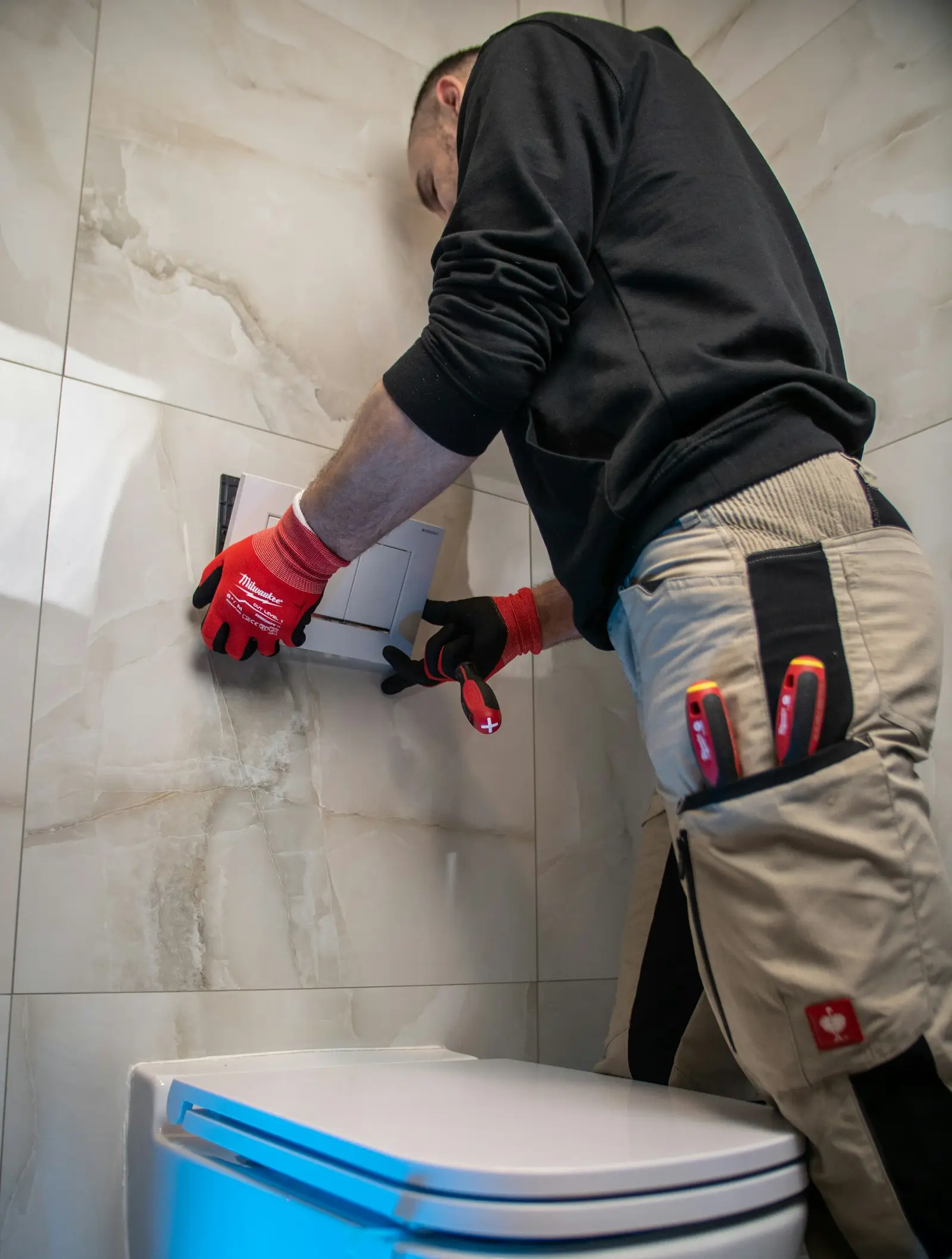 A Kessler plumber in red gloves working on a toilet