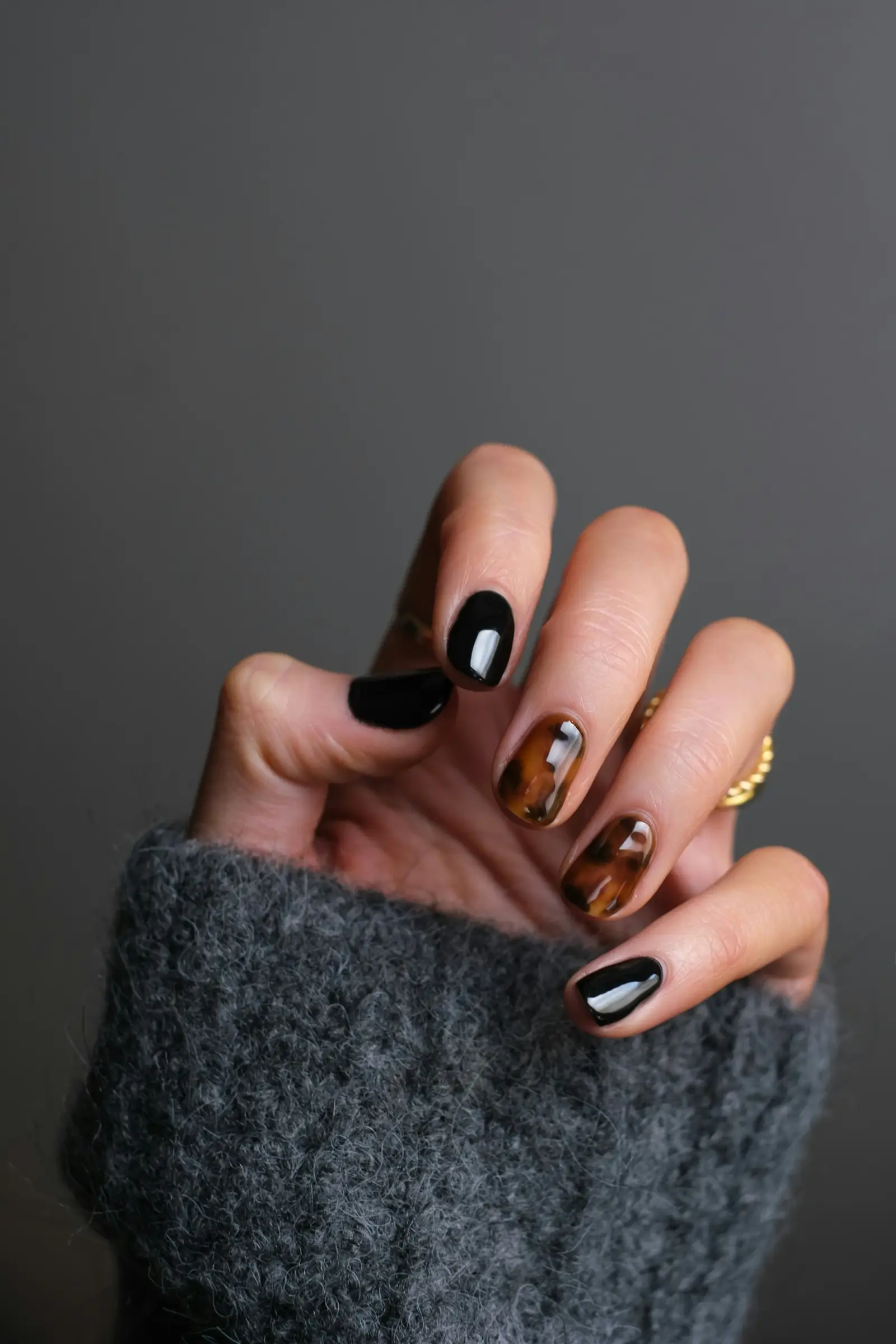 Black and tortoiseshell nails with a gold ring