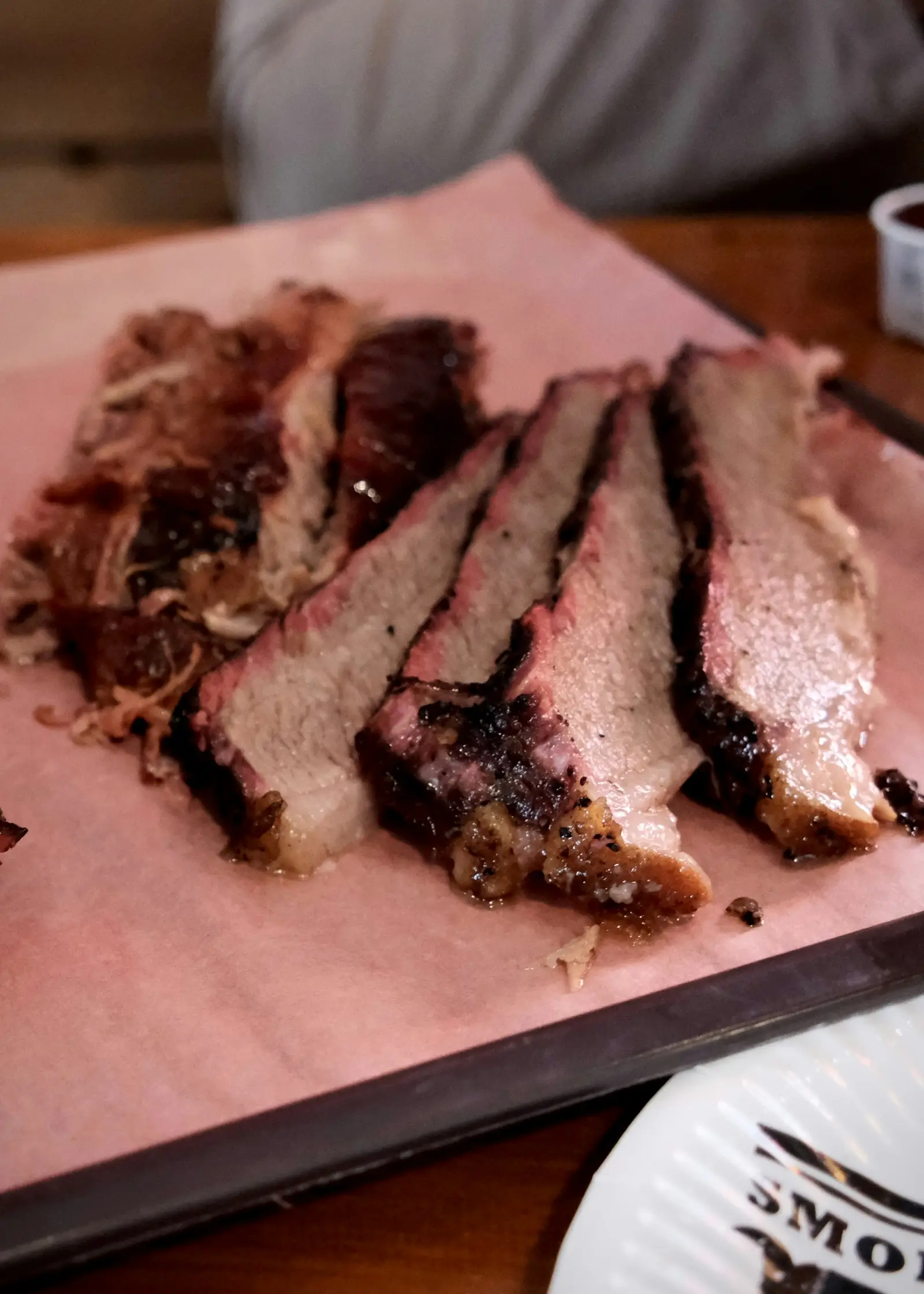 Sliced smoked brisket with a dark bark, resting on pink butcher paper